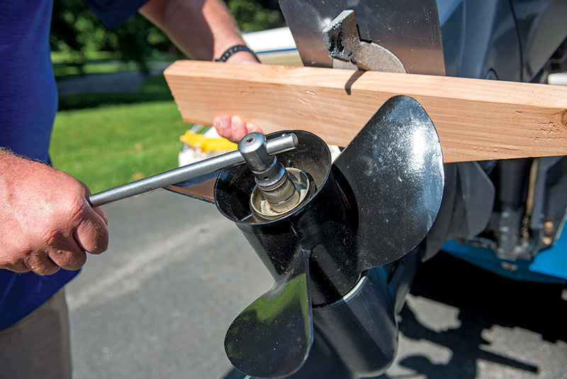 person unscrewing an outboard prop nut