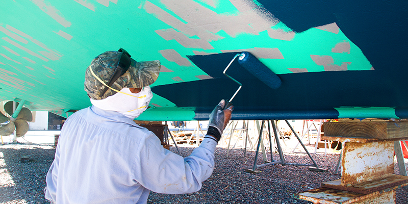 Man rolling bottom paint on to boat hull