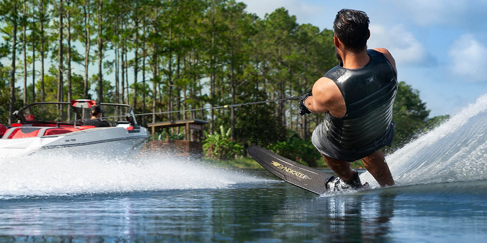 Man waterskiing on a lake, pulled by a speed boat