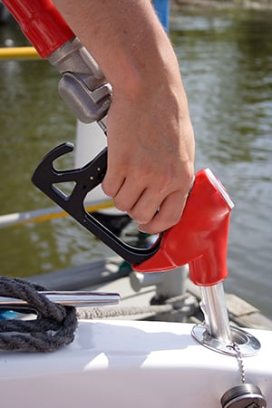 Hand holding gas nozzle inserted into deck fill for fuel tank