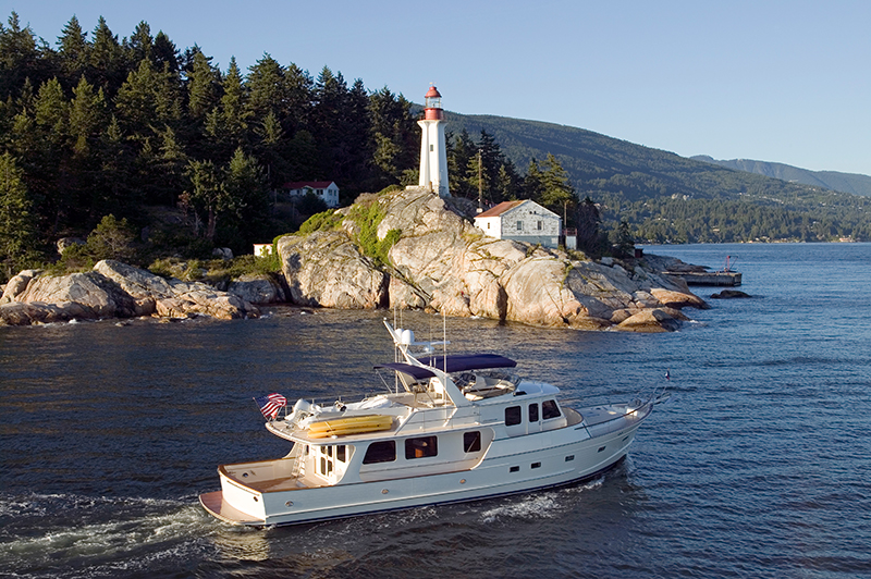 Trawler motoring near shore with lighthouse in background