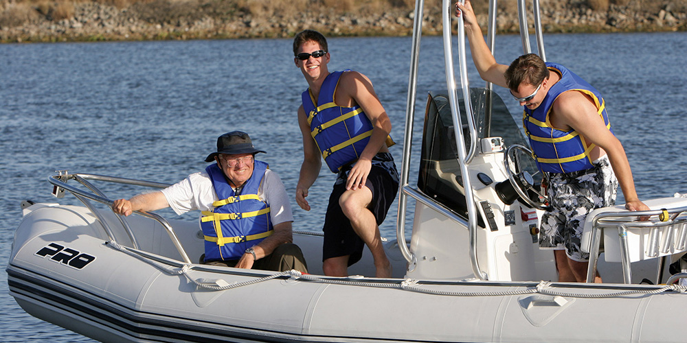 Three men wearing West Marine Runabout Life Jackets in an inflatable boat
