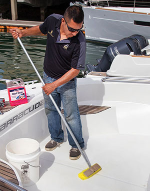 Man scrubbing cockpit deck to keep scuppers clear