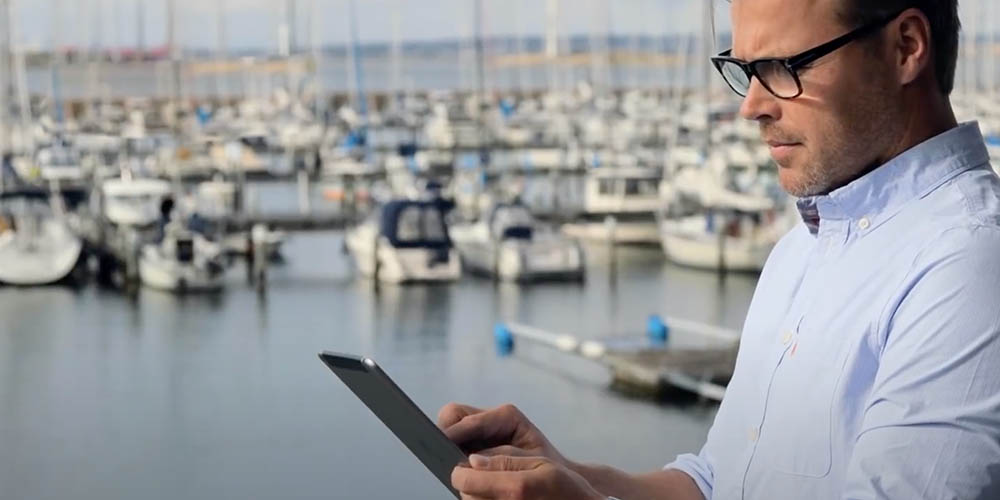 person using a tablet with a harbor in the background