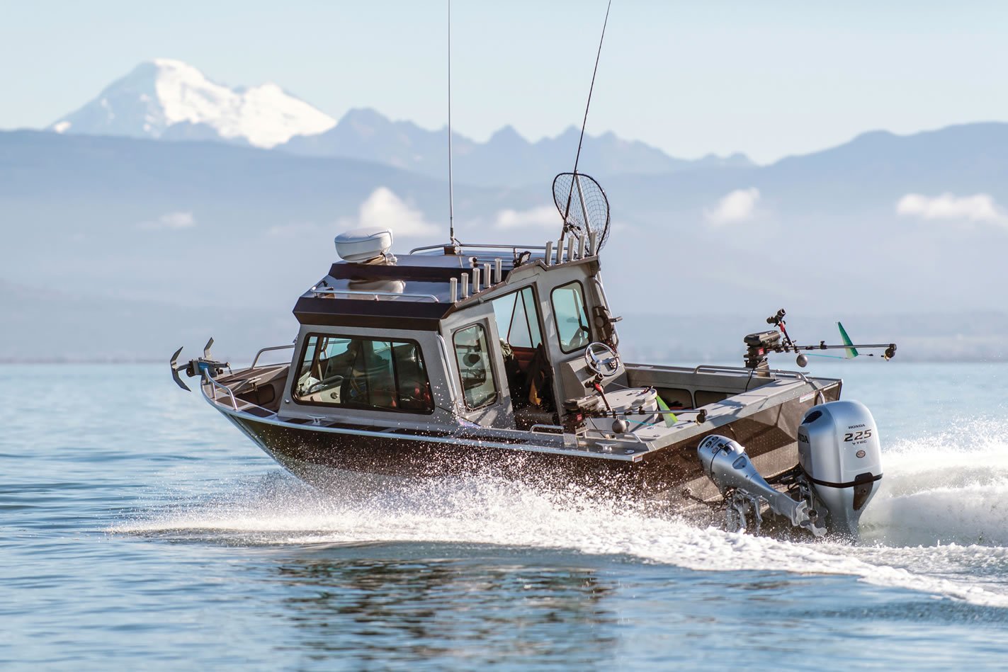 a boat moving through the water with a 225 horsepower Honda outboard and a 9.9 horsepower Honda outboard attached