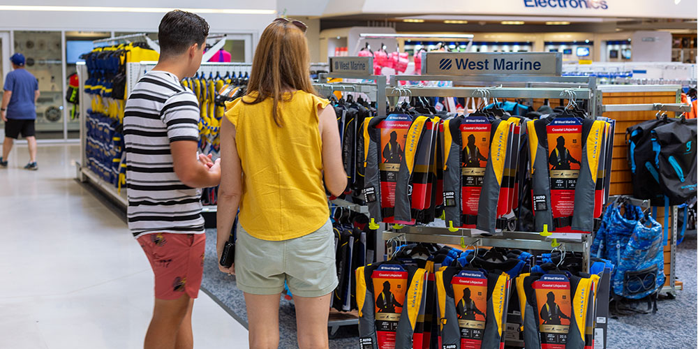 Two people in West Marine store looking at life jacket selection.