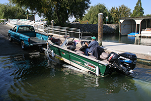 Pickup truck at launch ramp hitched to submerged trailer with boat on it