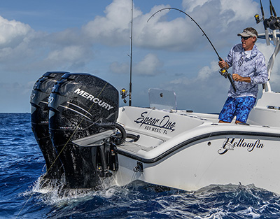 Angler at stern of boat battling fish with heavy spinning gear